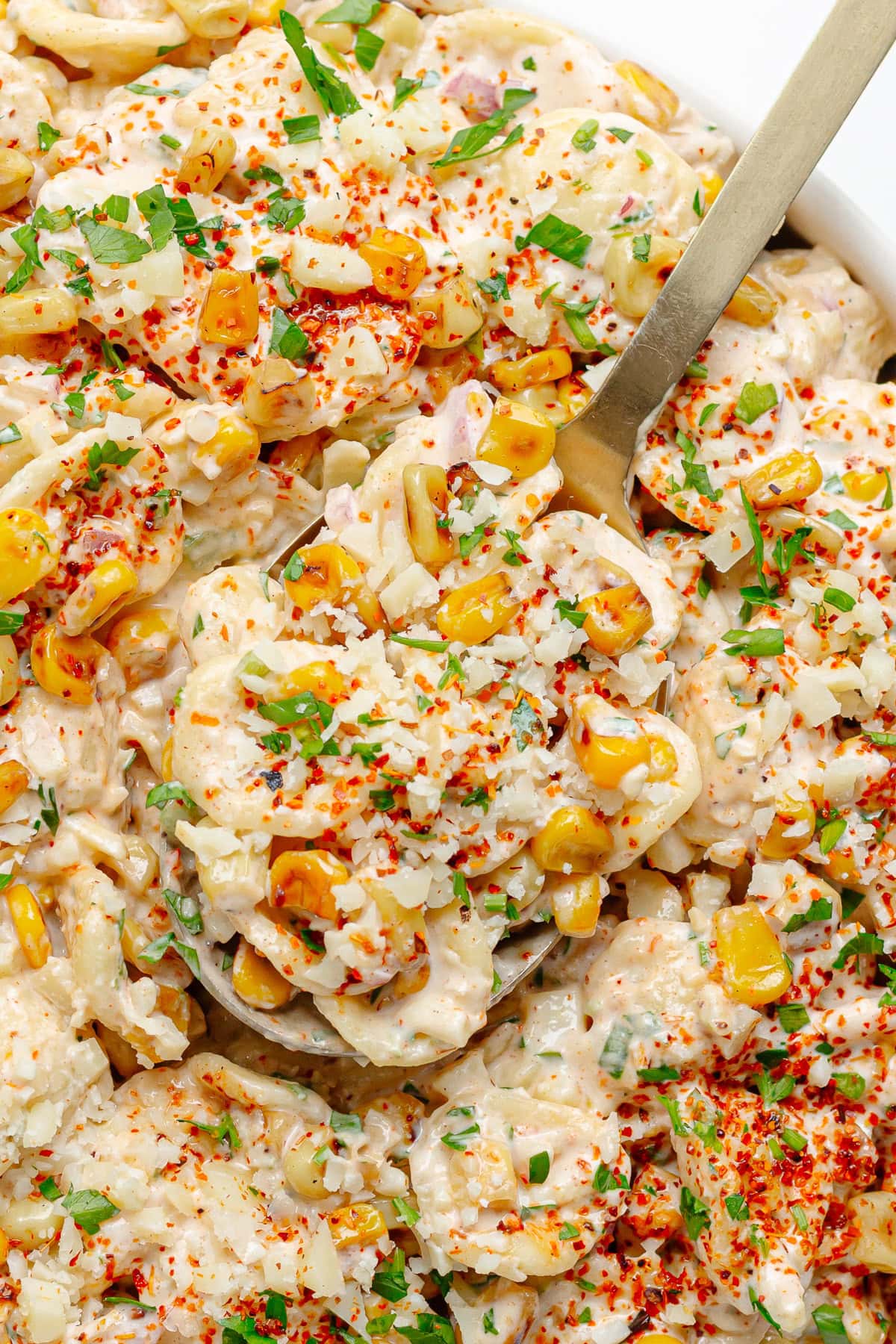 Closeup of a serving spoon scooping up street corn pasta salad.