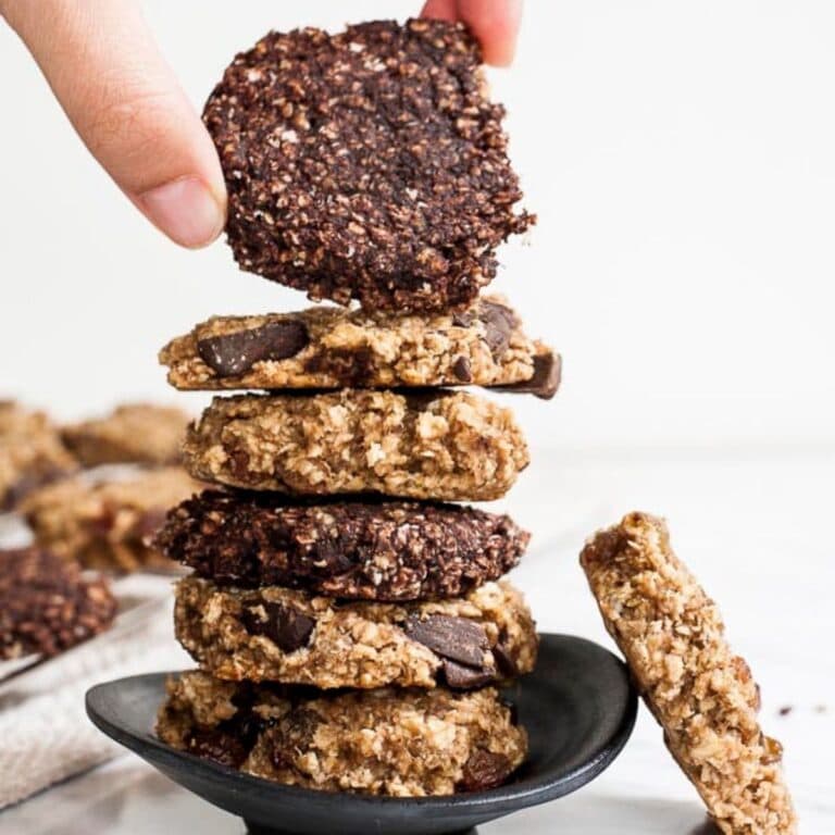 Hand grabbing top cookie from a stack of banana peanut butter oatmeal cookies.