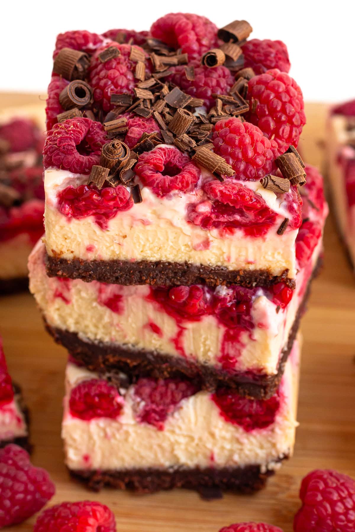 Stack of chocolate raspberry cheesecake bars garnished with dark chocolate shavings.