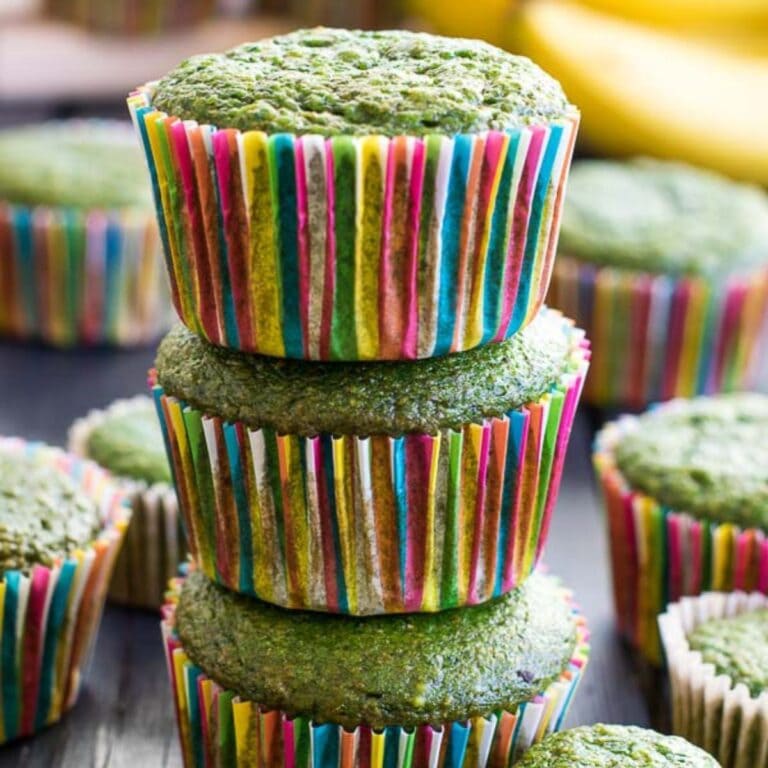 Stack of green muffins in rainbow colored muffin liners.