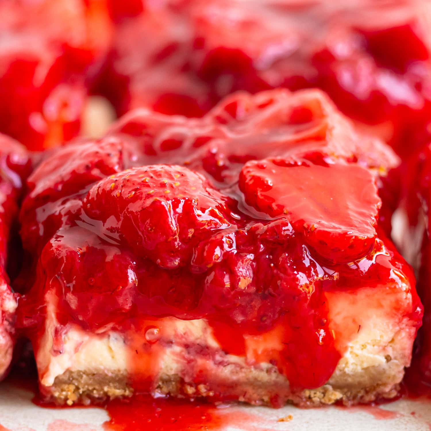 Closeup of strawberry cheesecake bars loaded with strawberry topping.