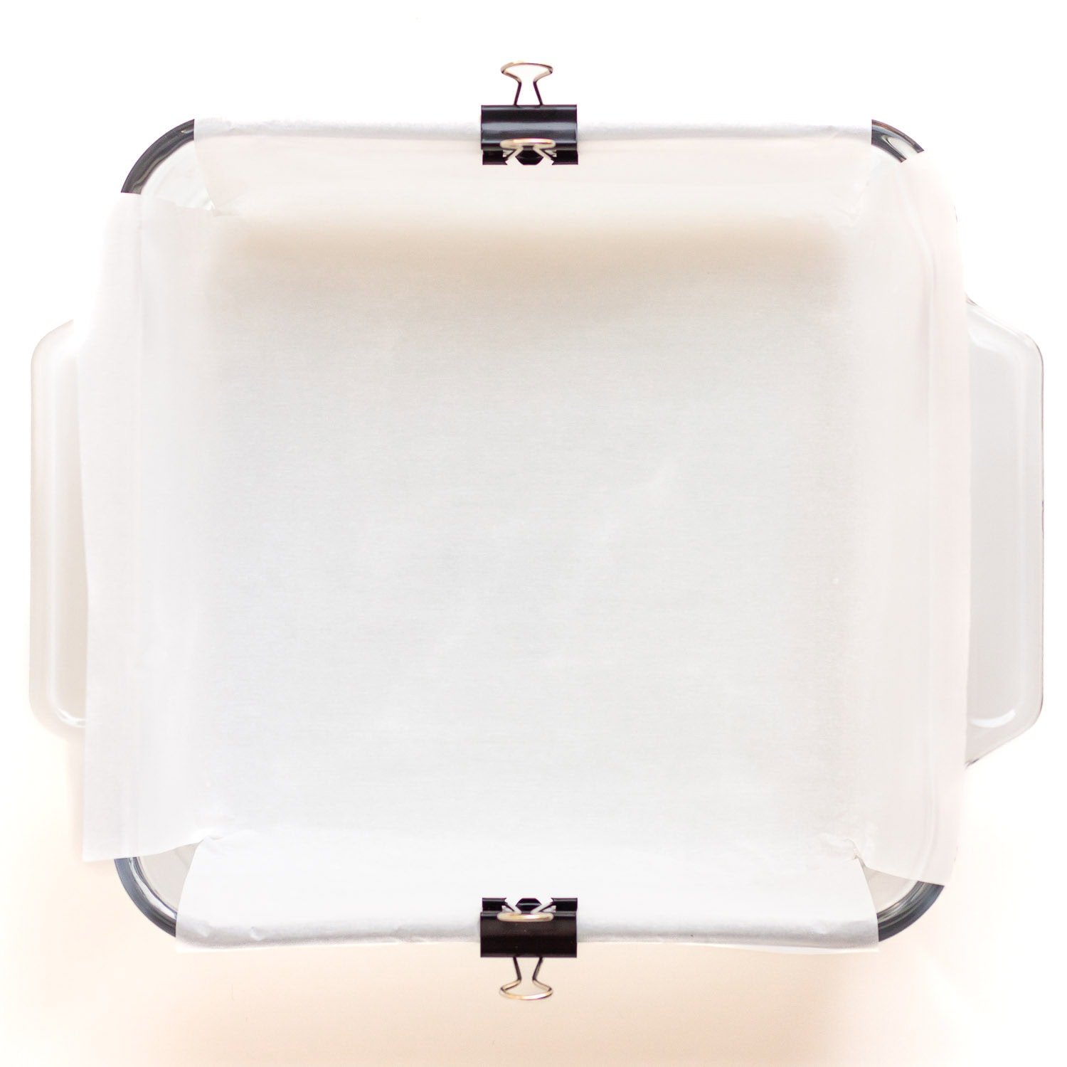 Parchment paper lined square glass baking dish.