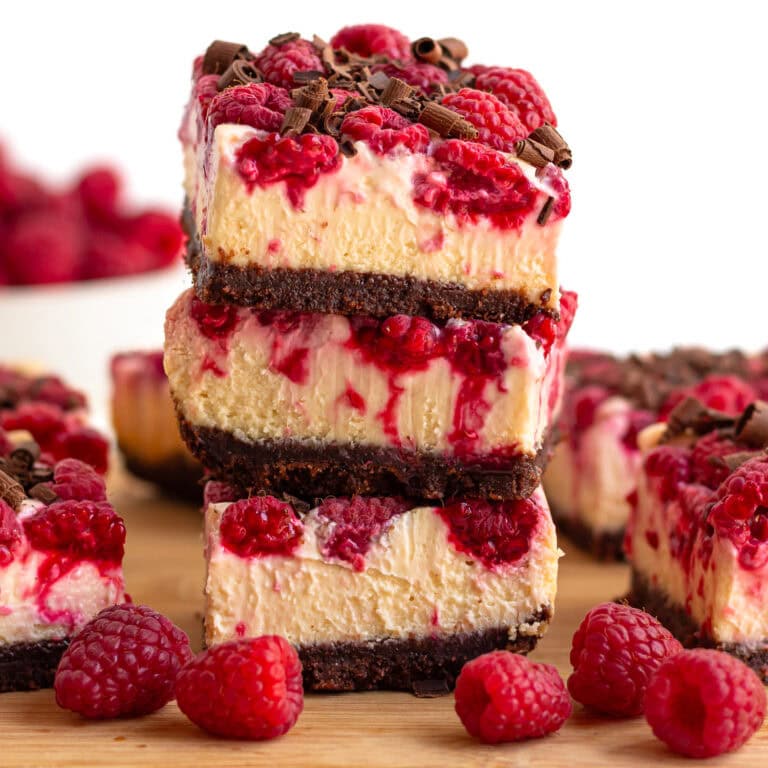 Stack of raspberry cheesecake bars garnished with dark chocolate shavings.