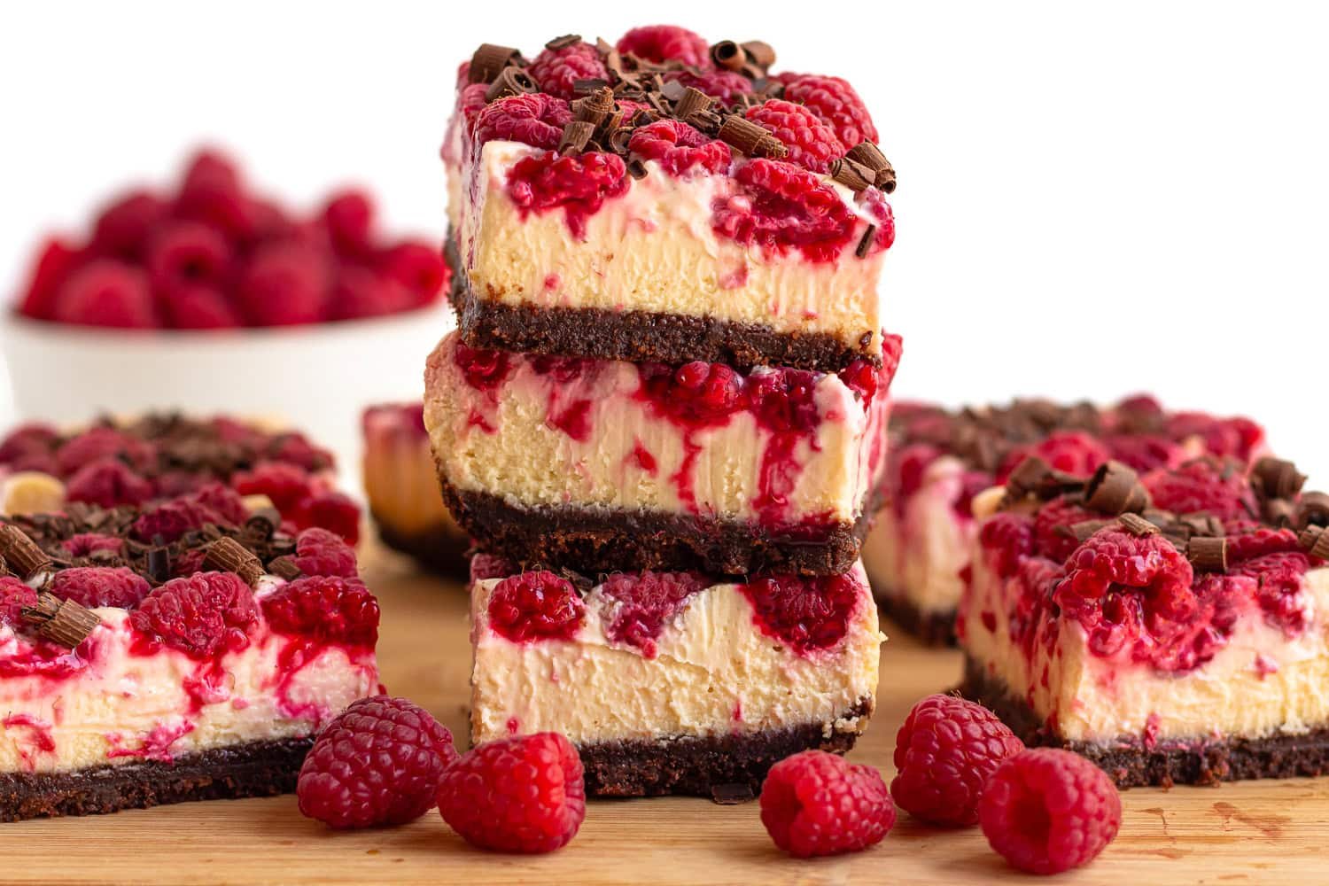 Raspberry chocolate cheesecake bars on a wooden board.