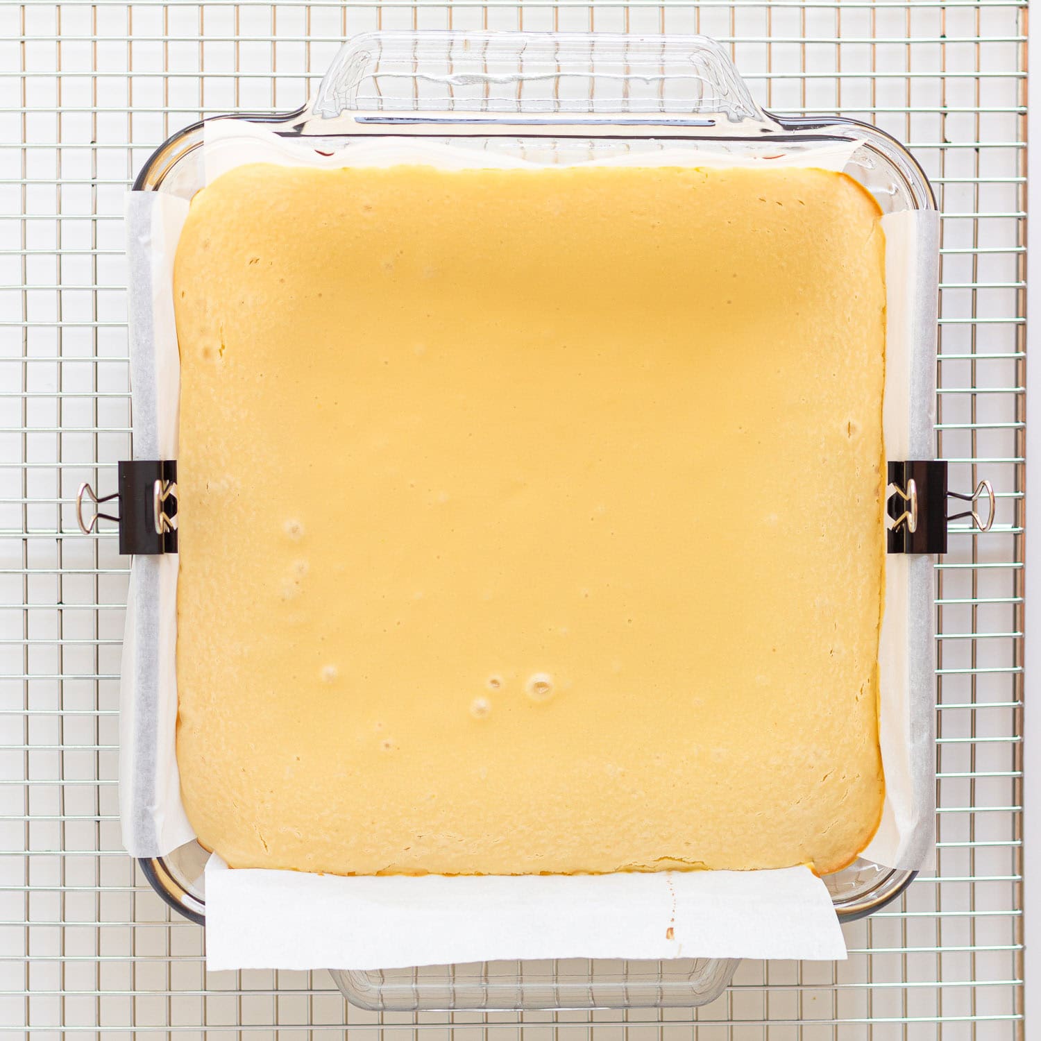 Baked vanilla cheesecake  in square baking dish ready for strawberry topping.