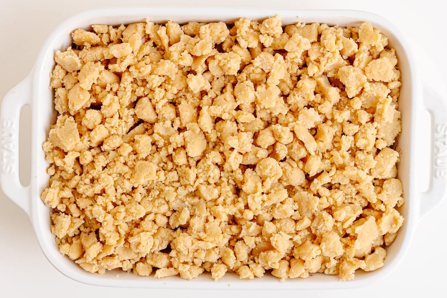 Unbaked pear crumble in white baking dish.