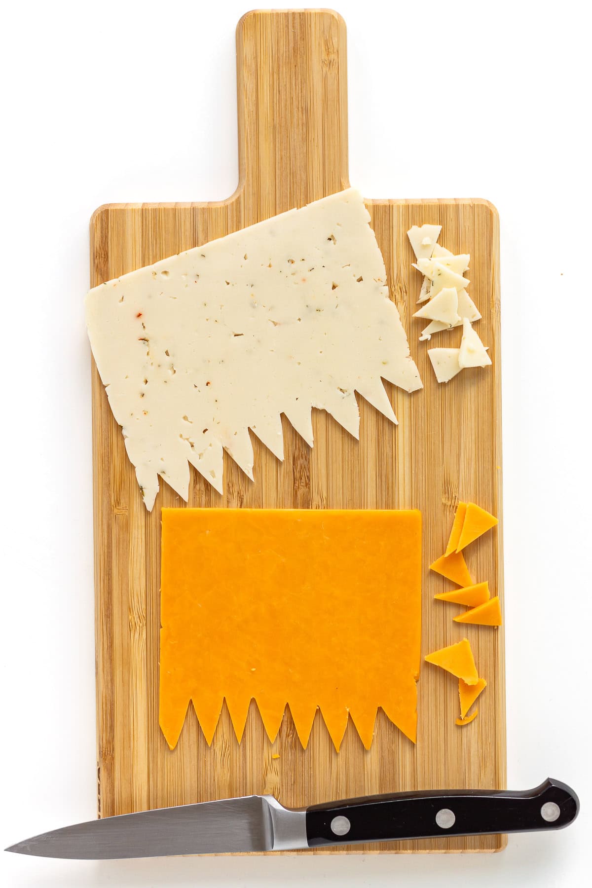 Two cheese slices on cutting board with zigzag pattern cut out along one edge.