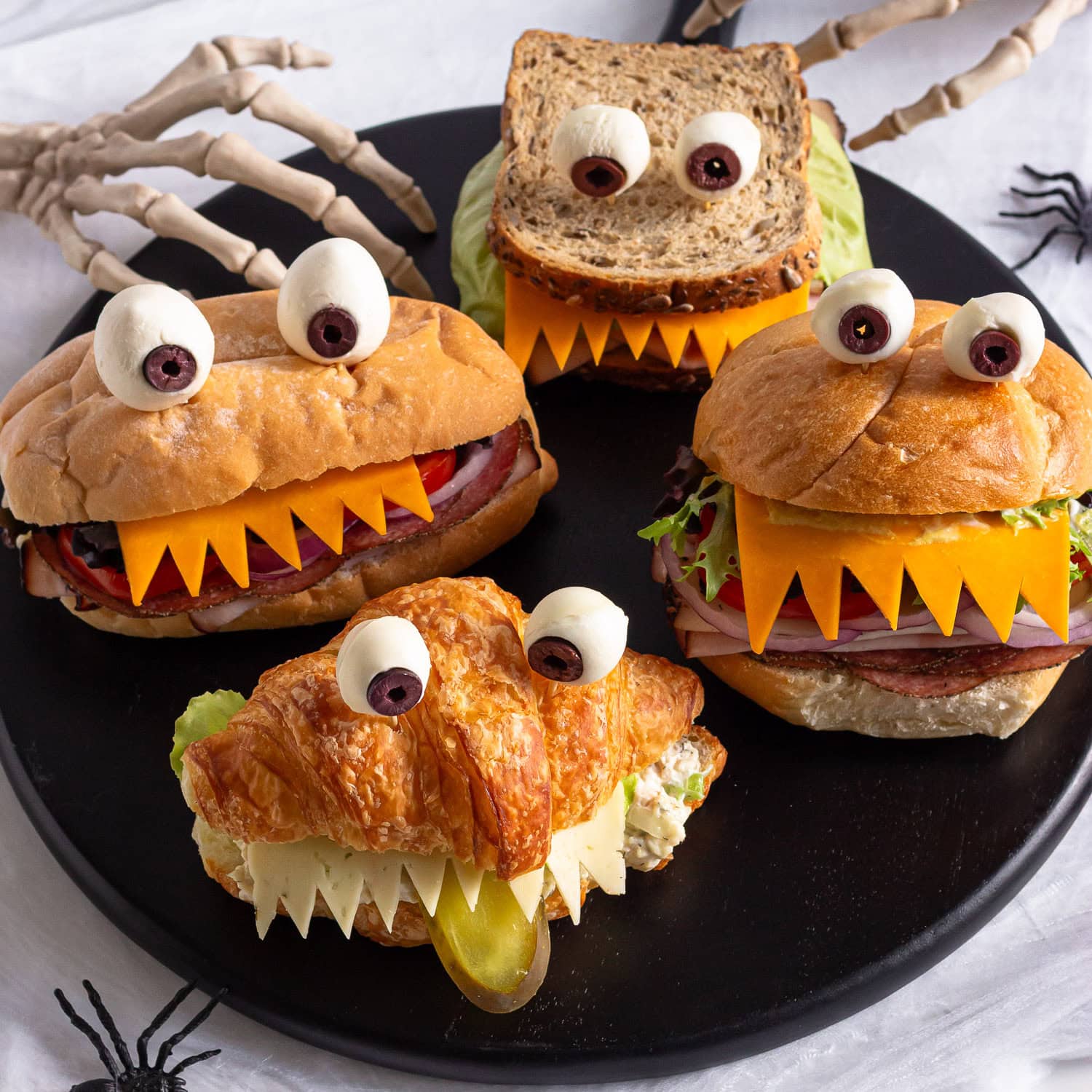 Halloween monster sandwiches on a black round serving board.