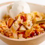 Spoonful of pear crumble being lifted from bowl.