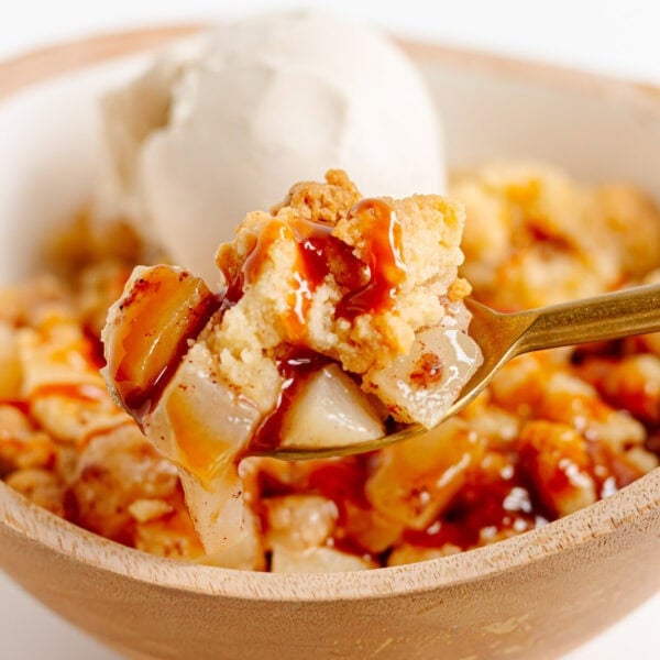 Spoonful of pear crumble being lifted from bowl.
