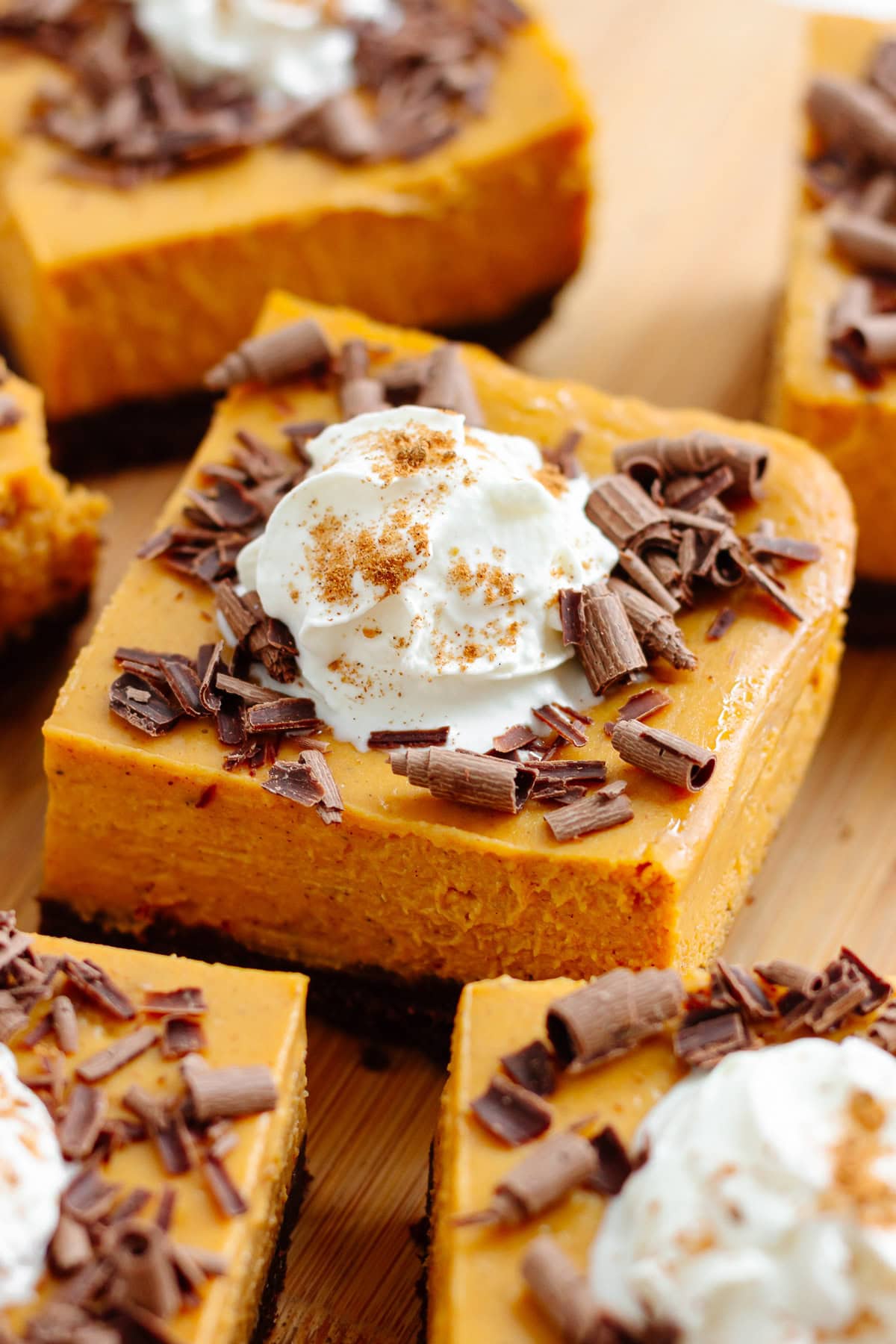 Pumpkin cheesecake bars on a wooden board.