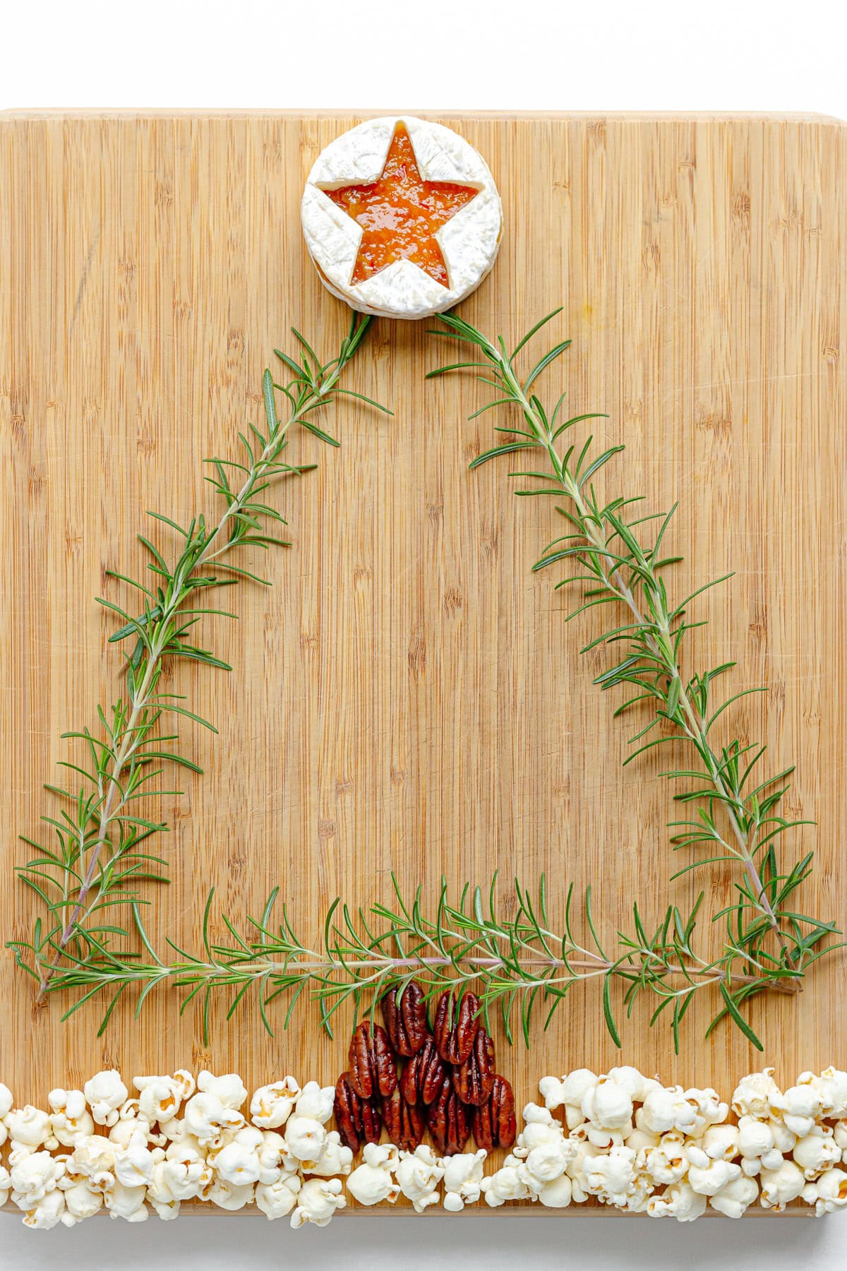 Outline of tree made with rosemary sprigs added to charcuterie board.