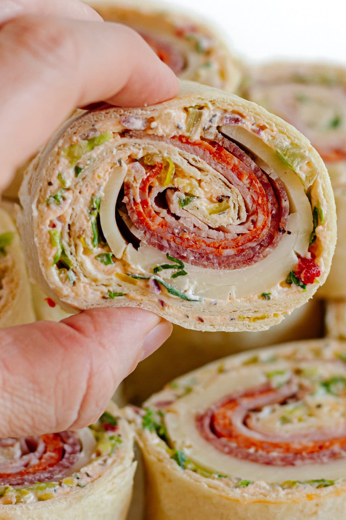 Hand grabbing an Italian pinwheel from a serving platter.