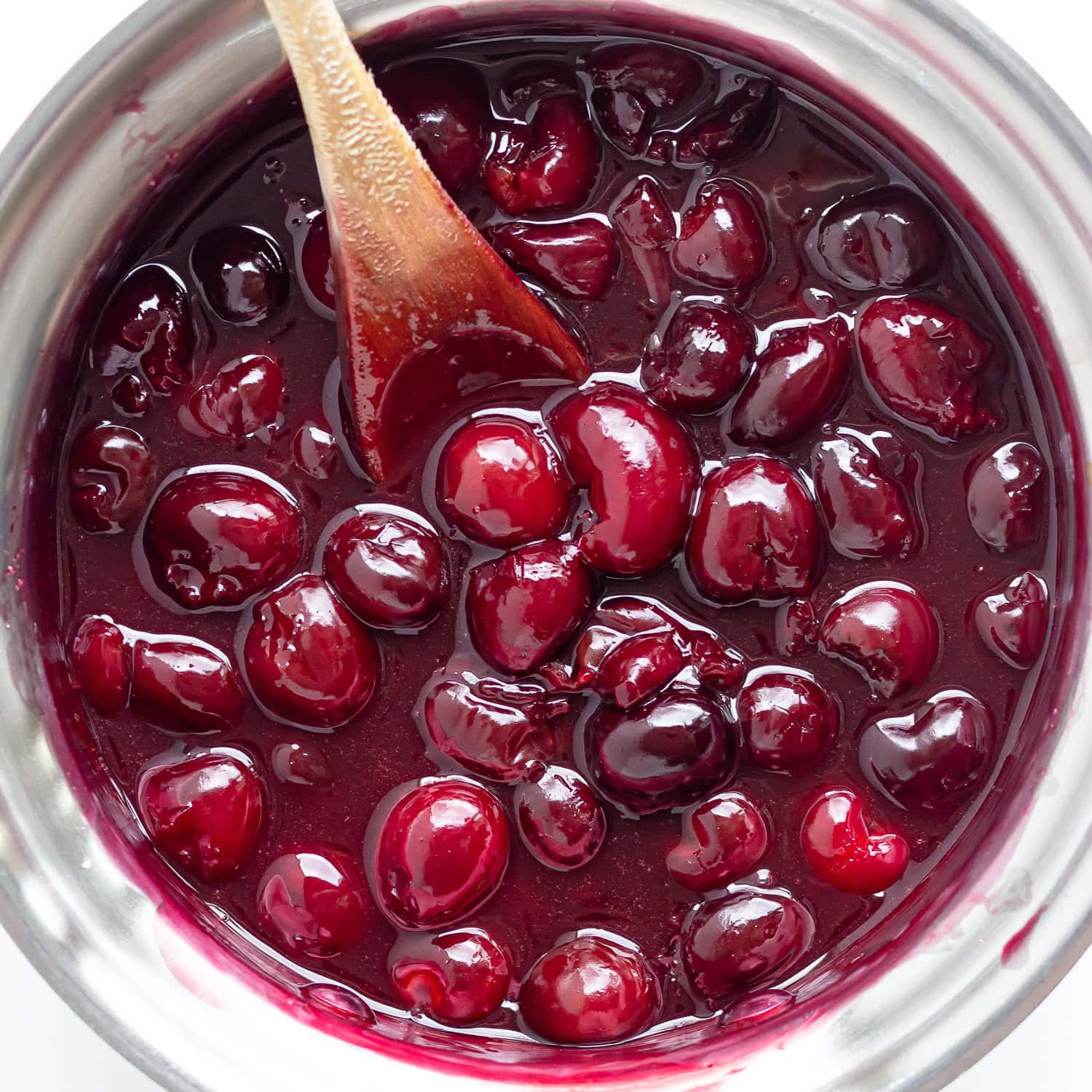 Cherry topping for cheesecake being stirred in a saucepan.