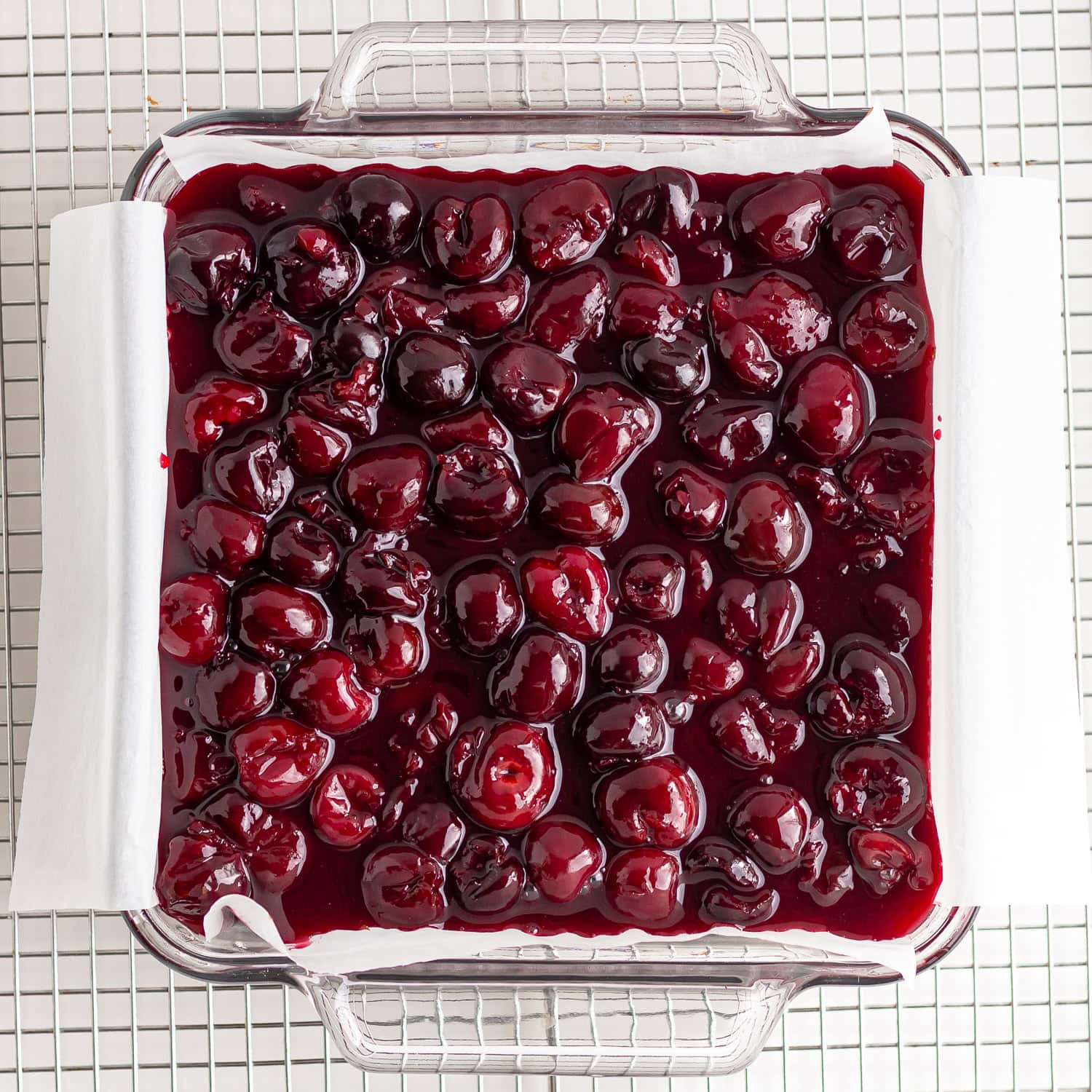 Baking dish of chocolate cheesecake with cherry topping.