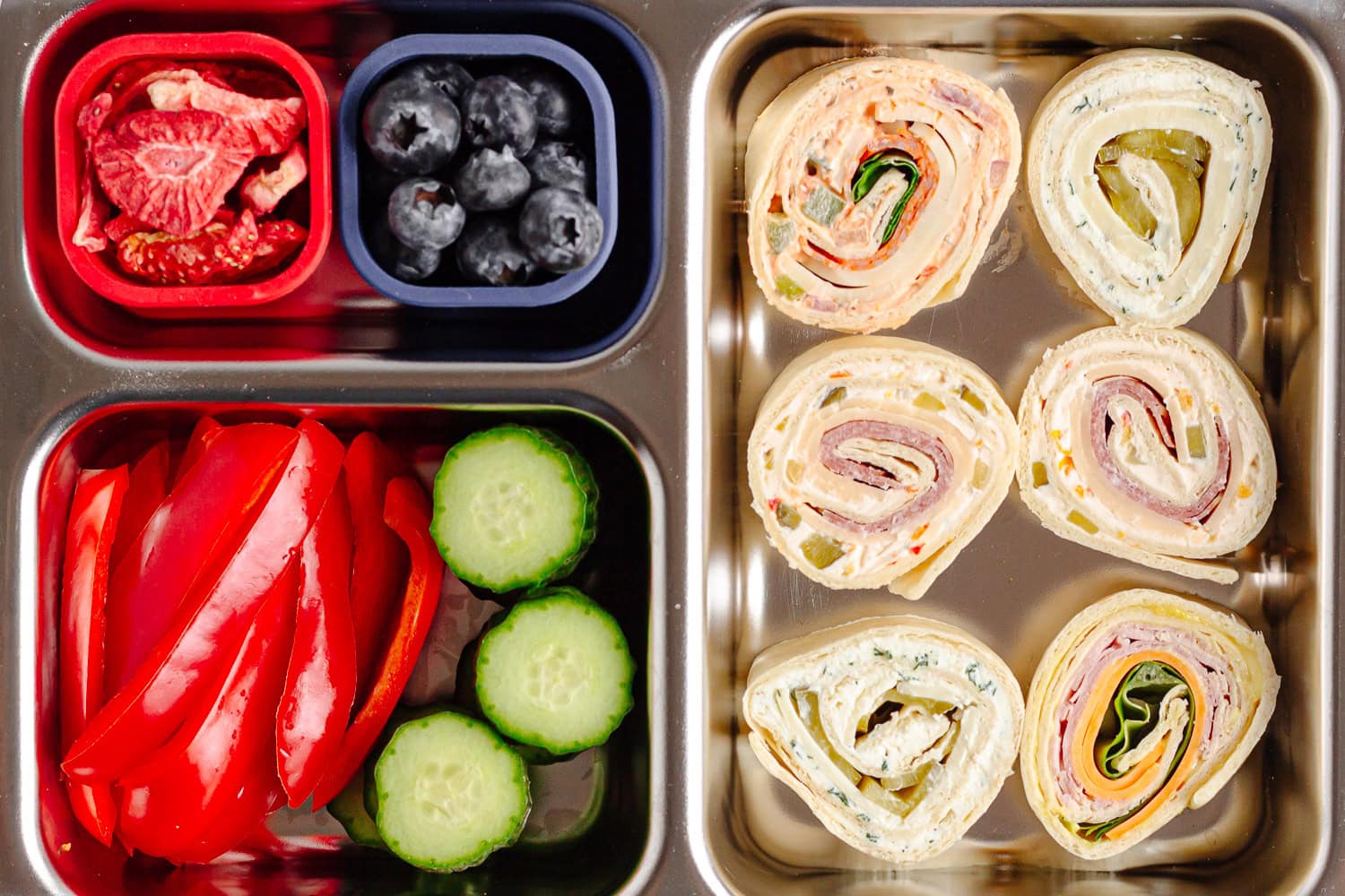 Lunch box filled with fruit, veggies and pinwheels.