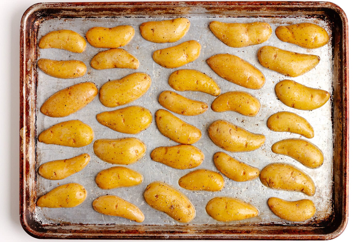 Halved fingerling potatoes arranged cut side down on a baking sheet for roasting.