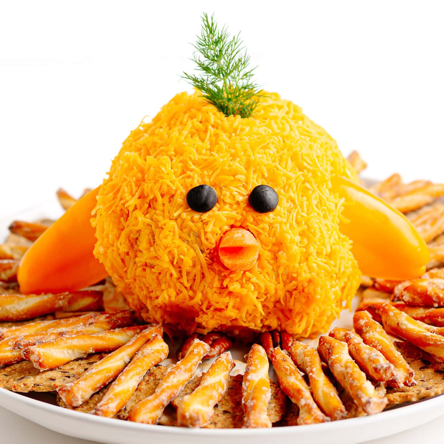 Baby chick cheese ball sitting in a nest made of pretzels and crackers.