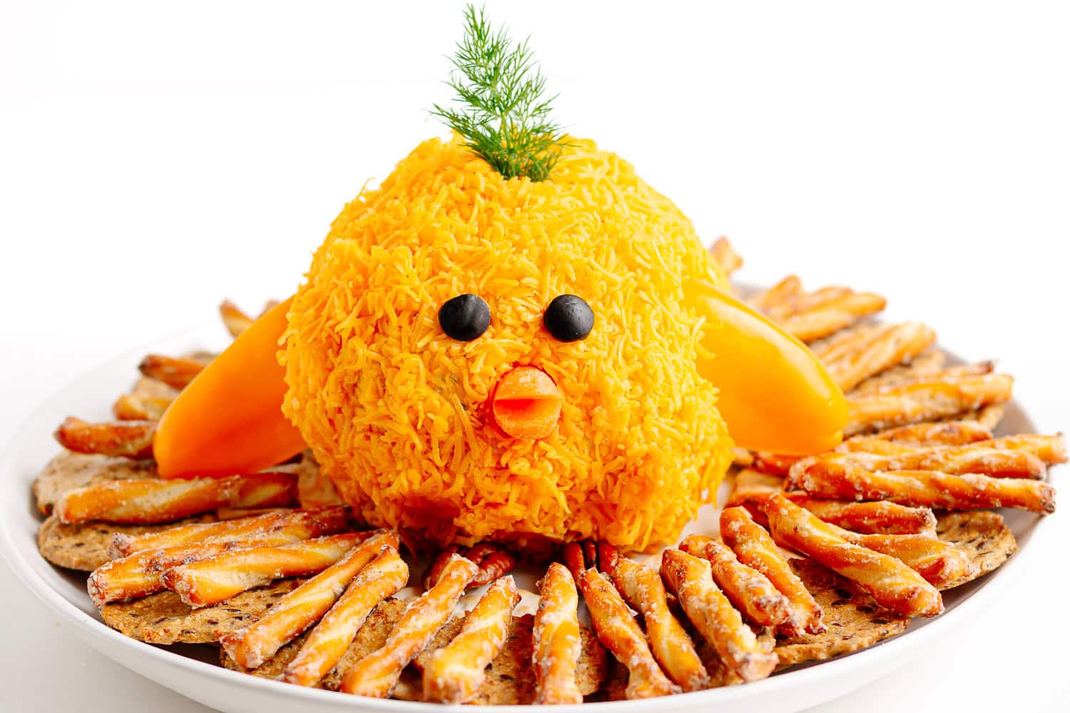 Baby chick cheese ball sitting in a nest made of crackers and pretzels.