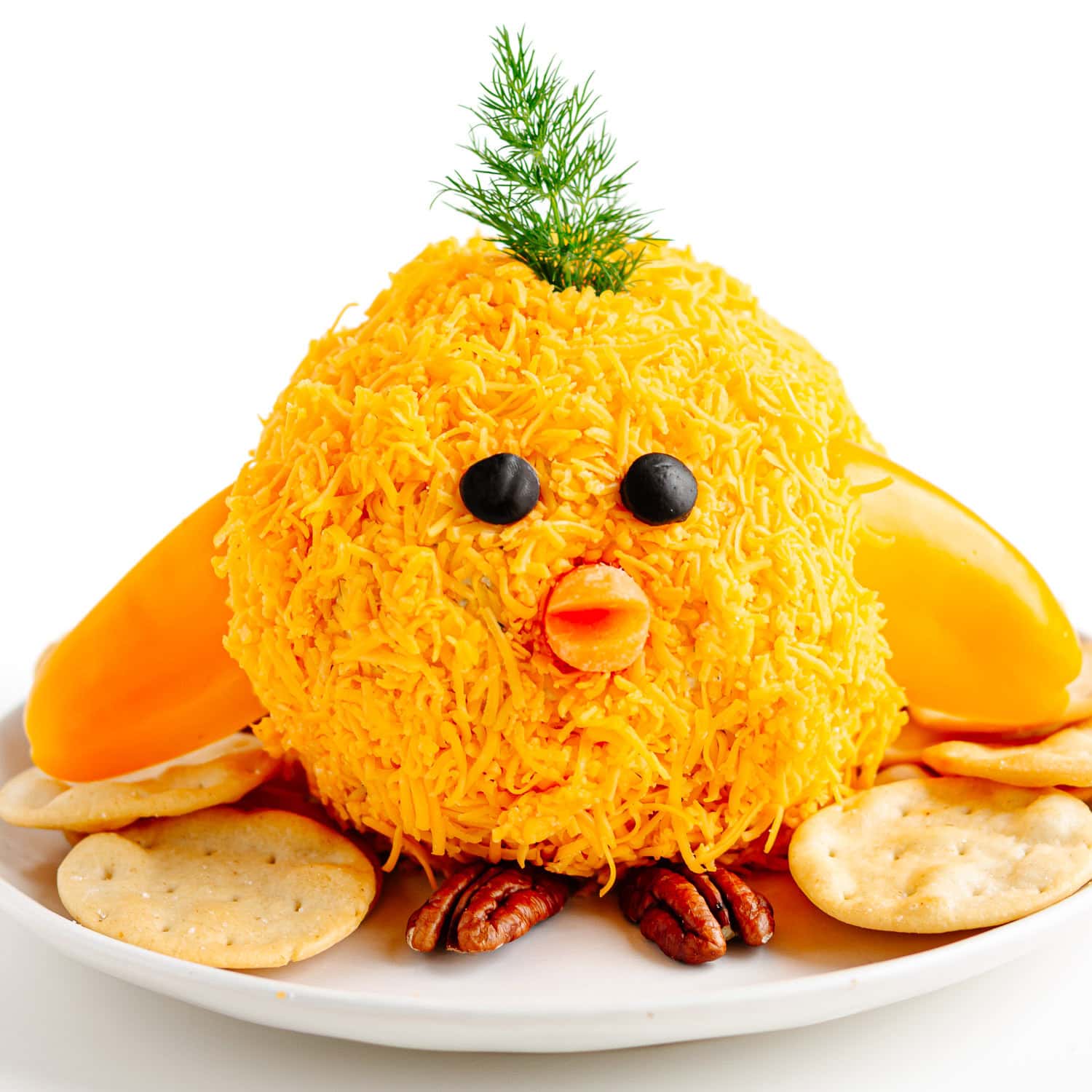 Easter cheese ball in the shape of a baby chick on a plate with crackers.