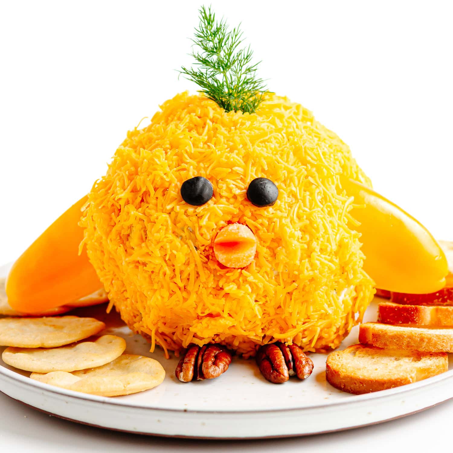 Easter cheese ball shaped into a baby chick on a plate with crackers.