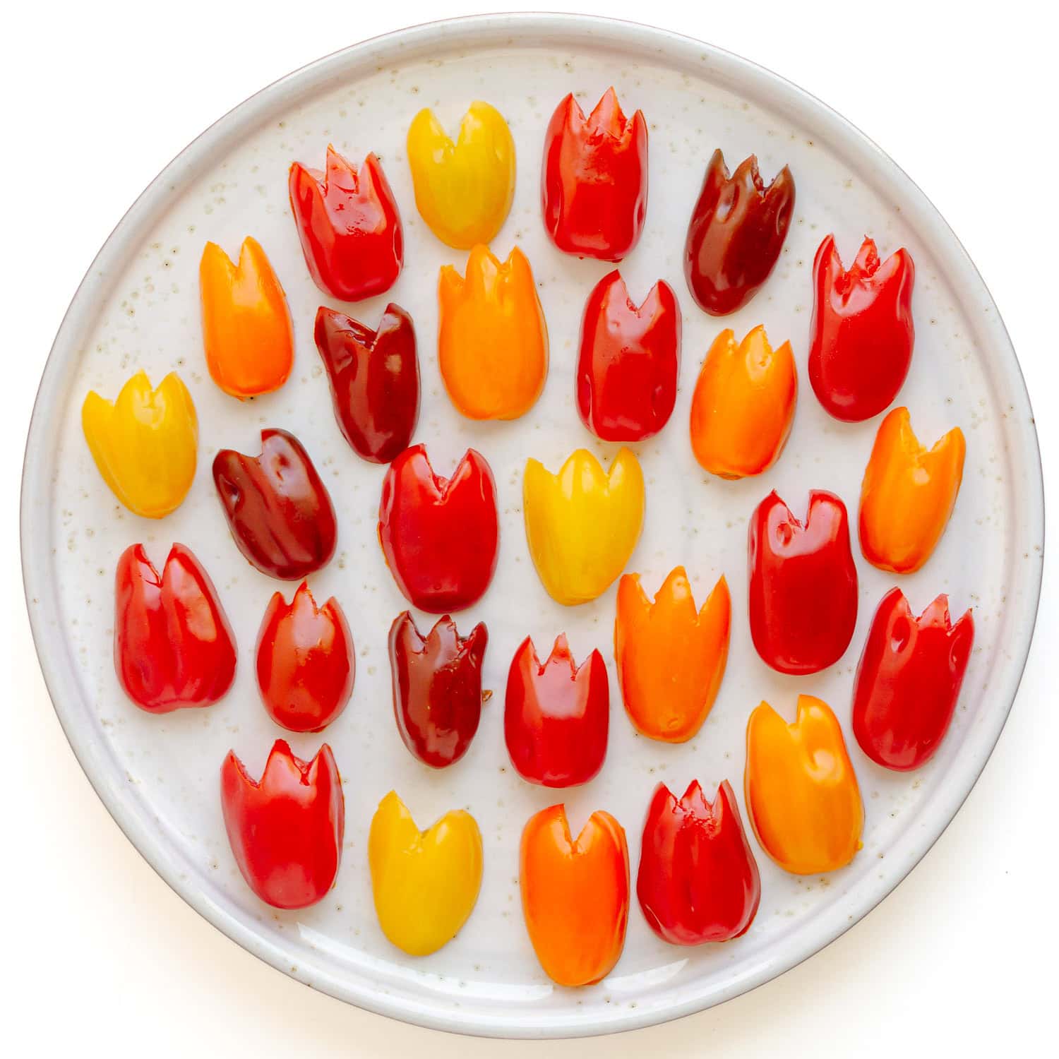Grape tomatoes cut to look like tulip heads sitting on a plate.