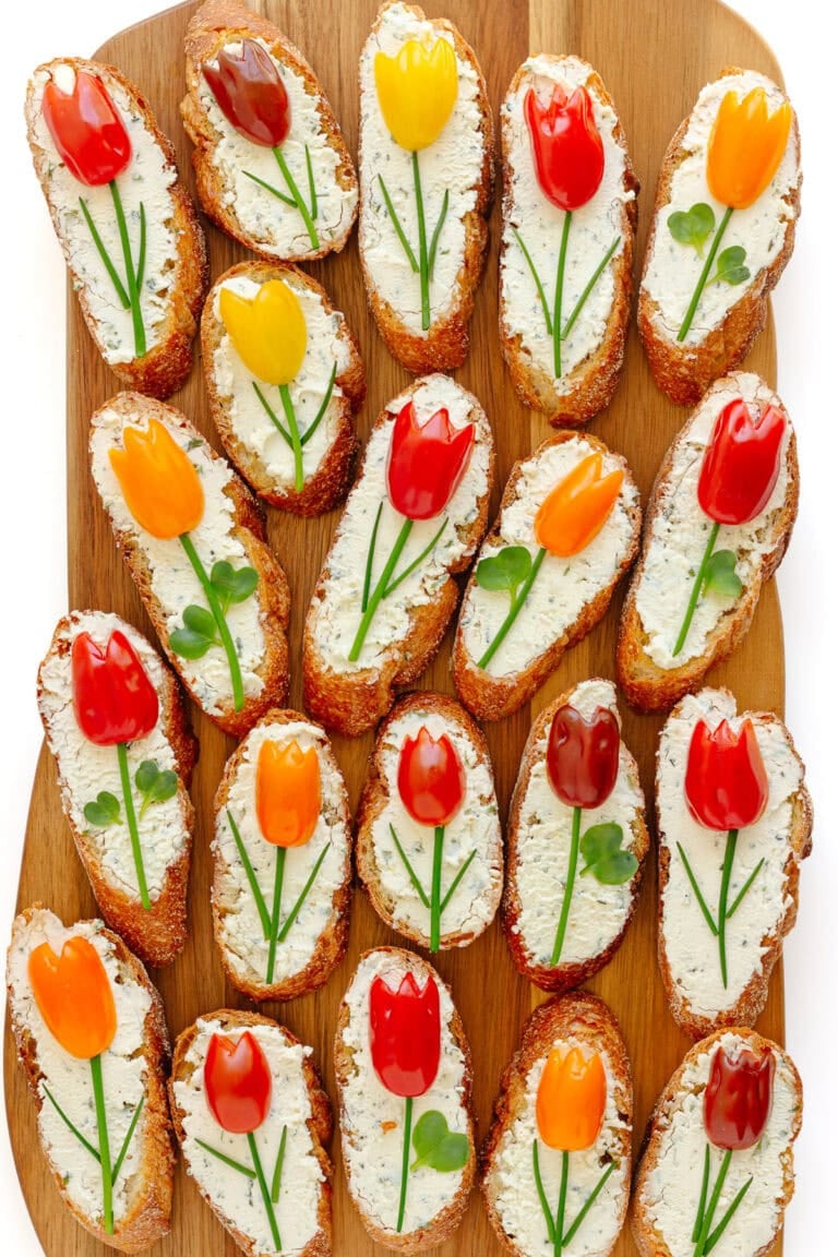 Spring crostini with tomato tulips on a wood serving board.
