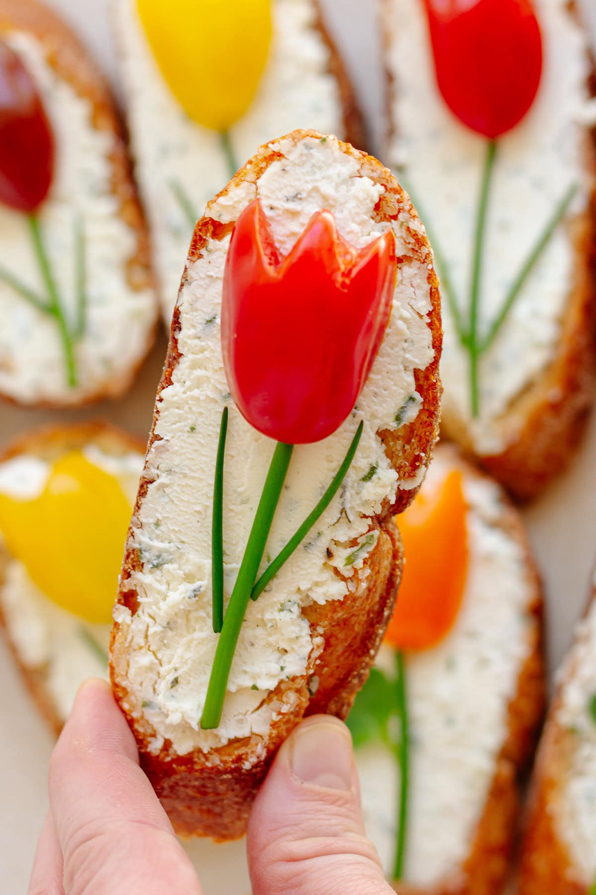 Hand picking up a tomato tulip crostini.
