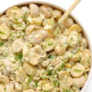 Dill pickle potato salad in a serving bowl with serving spoon.