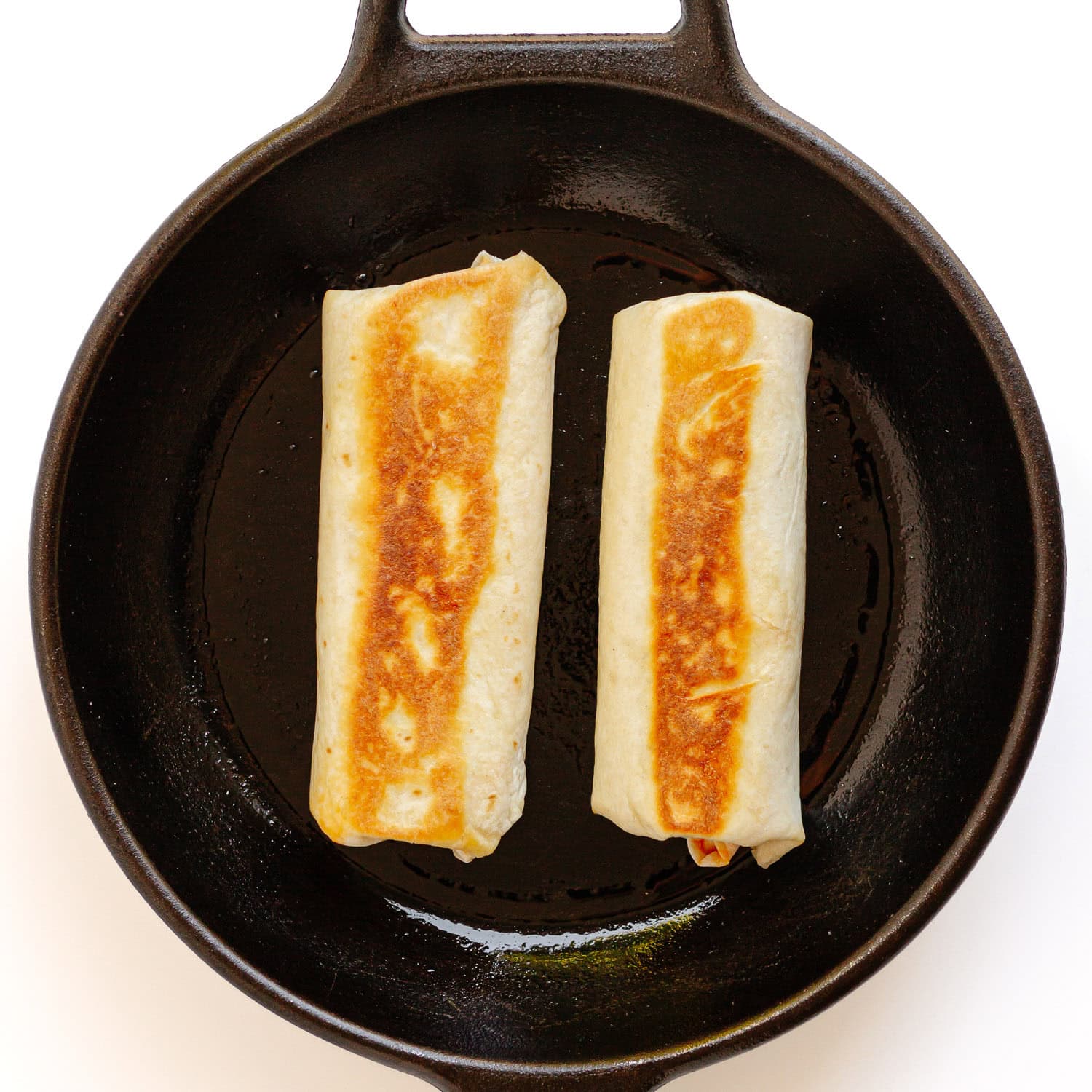 Toasted tuna melt wraps in cast iron skillet.