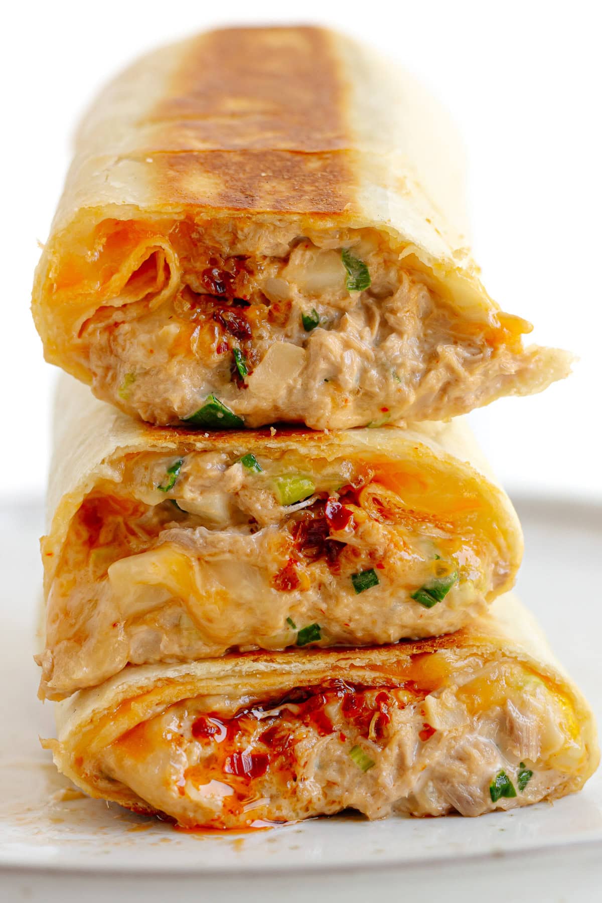Three tuna melt wrap halves piled on a plate.