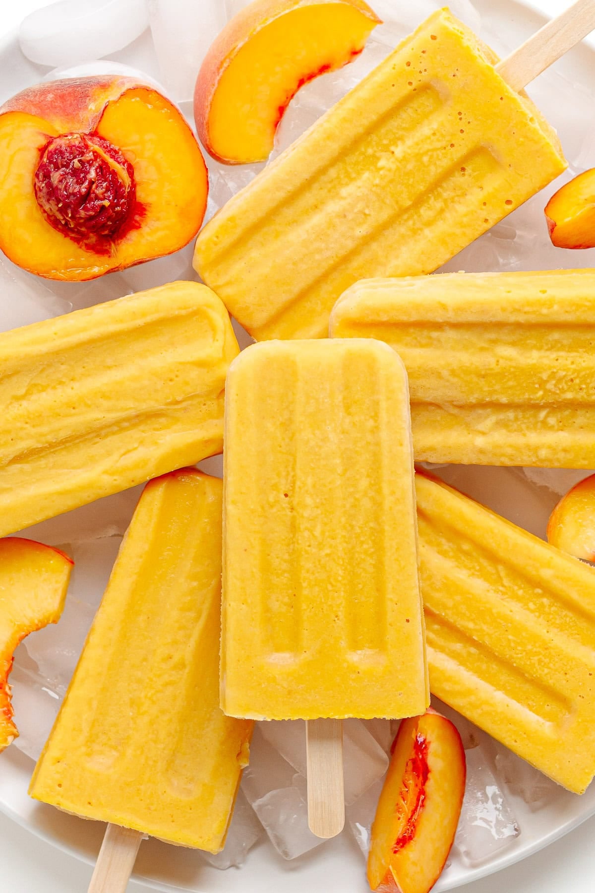 Creamy peach popsicles piled up on ice.