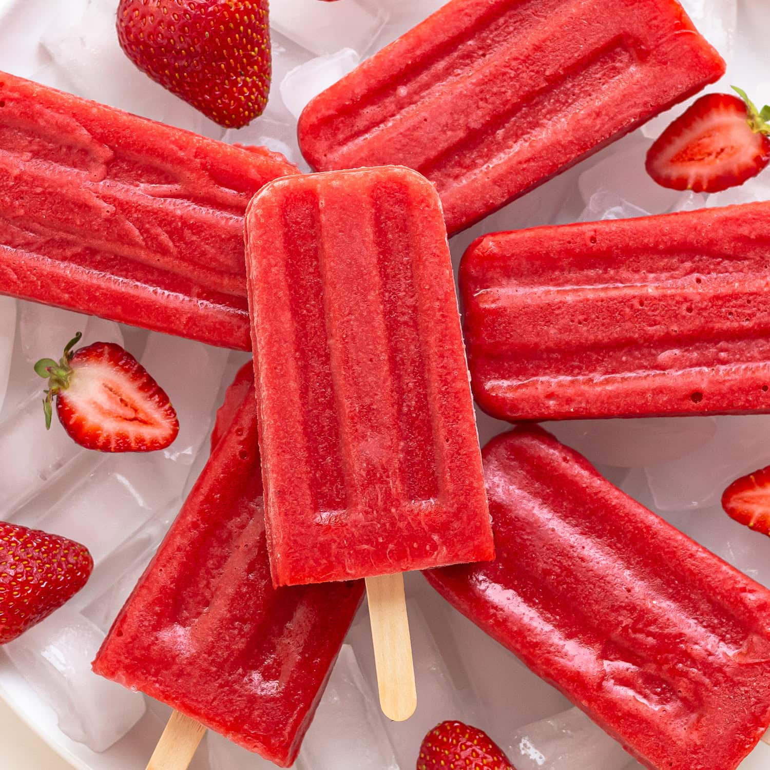 Strawberry popsicles arranged on ice.