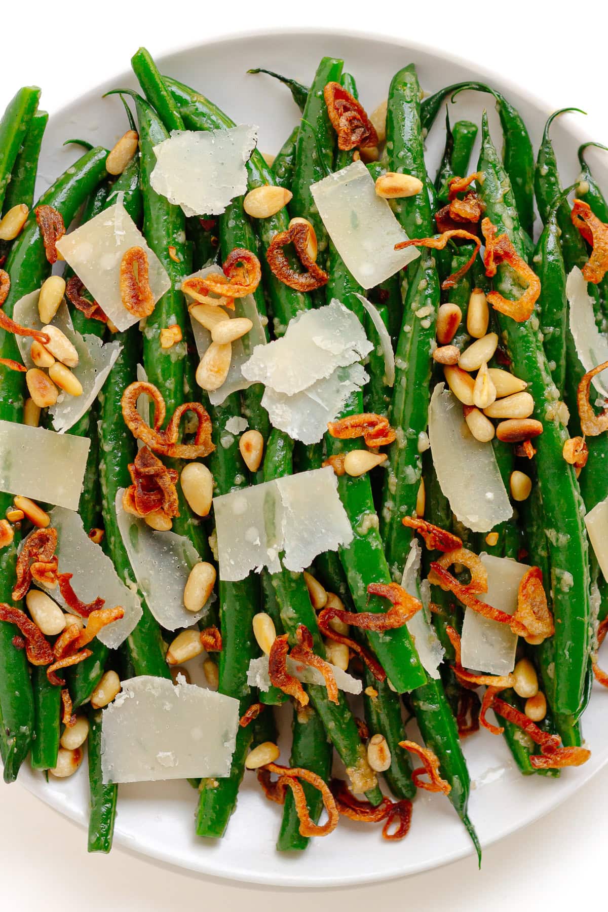 Garlic parmesan green beans garnished with toasted pine nuts, parmesan shavings, red chili flakes and crispy shallots.