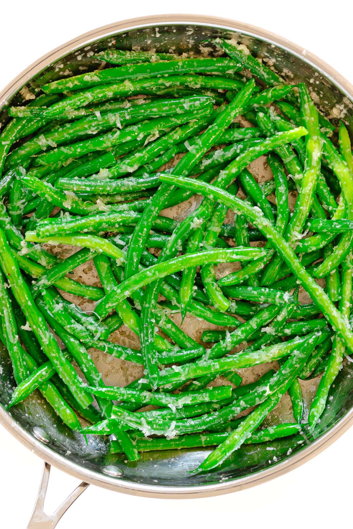 Sauteed green beans with garlic butter and parmesan in a stainless steel skillet.