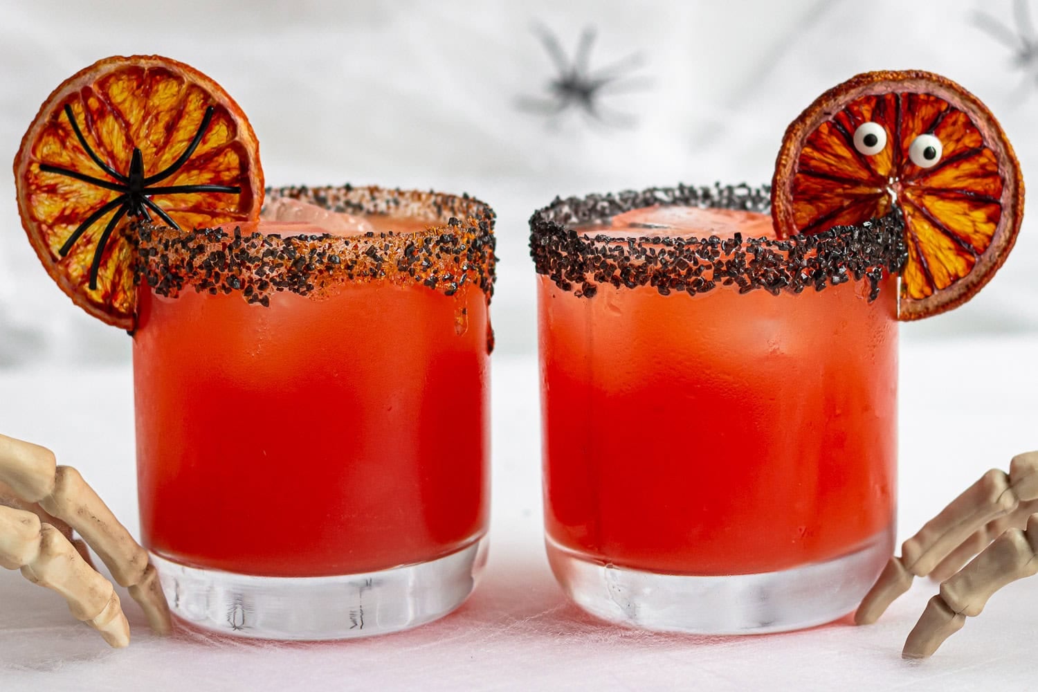 Two Halloween margaritas garnished with spooky blood orange slices.